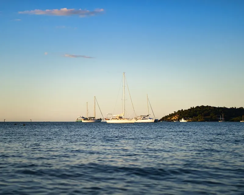 Sailing boats anchored off a wooded island near Airlie Beach at dusk